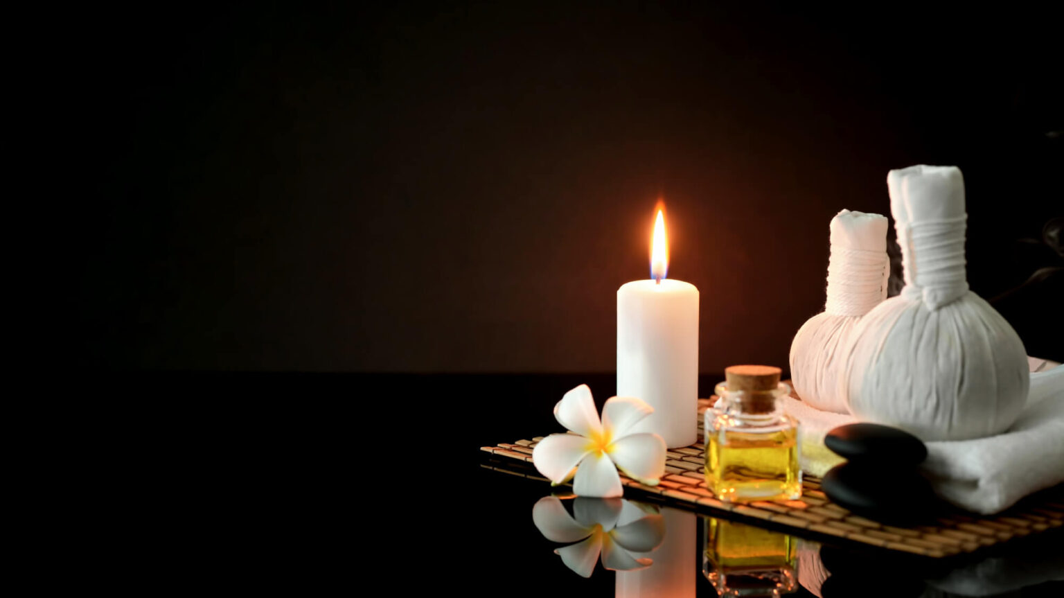 cropped shot spa treatment accessories with white towel candle aroma oil dark background